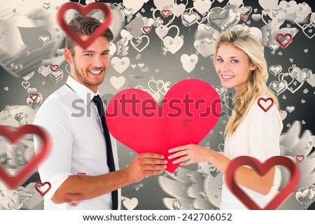 Attractive young couple holding red heart against grey valentines heart pattern