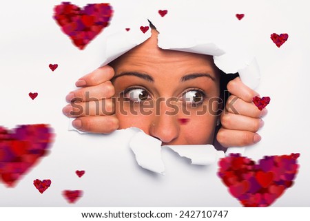 Young woman looking through paper rip against hearts