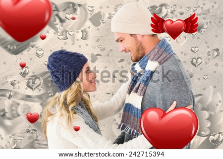 Attractive couple in winter fashion hugging against grey valentines heart pattern