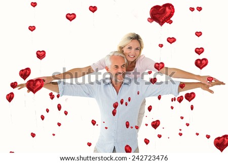 Smiling couple posing with arms out against red heart balloons floating