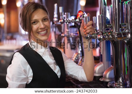 Happy barmaid smiling at camera in a bar