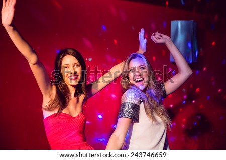 Pretty friends dancing and smiling at the nightclub