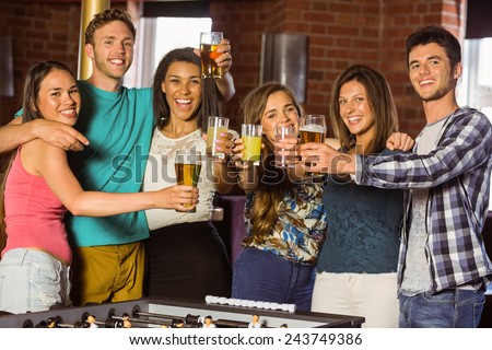 Portrait of happy friends toasting with mixed drink and beer in a bar