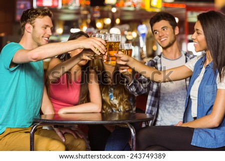 Happy friends toasting with drink and beer in a pub