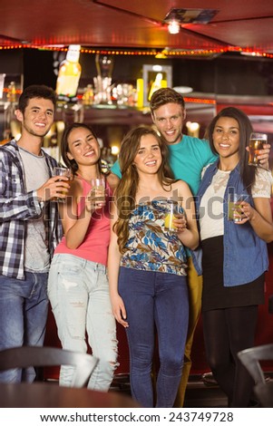 Smiling friends drinking beer and mixed drink in a bar