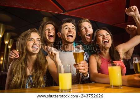 Happy friends drinking beer and cheering together in a bar
