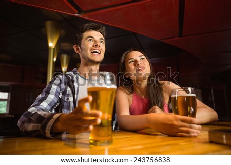 Smiling friends drinking beer together in a bar