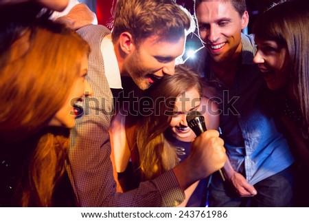 Happy friends singing karaoke together at the nightclub