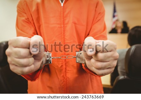Prisoner in handcuffs clenching fists in the court room