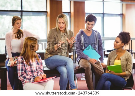 Happy students talking with their teacher in the library