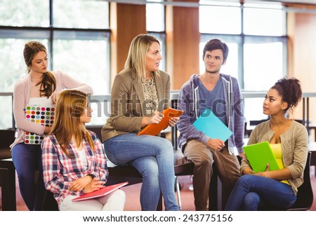 Happy students talking with their teacher in the library