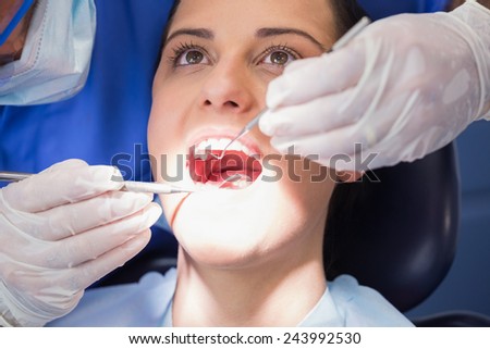 Dentist examining a patient with angle mirror and sickle probe in dental clinic