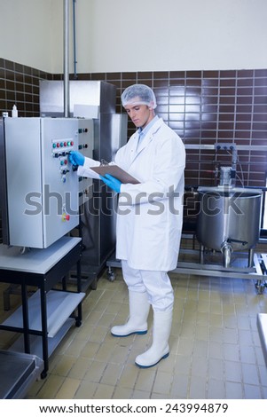 Focused biologist with safety gloves holding clipboard in the factory