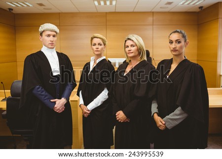 Four serious judges standing while wearing robes in the court room