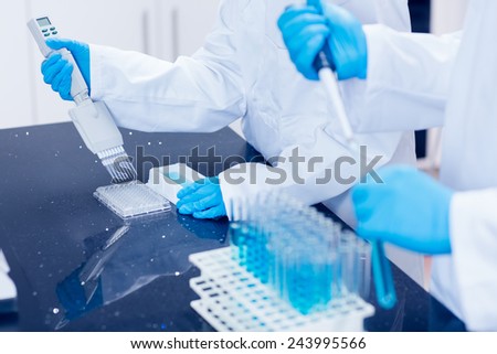 Science students using pipettes to fill test tubes at the university