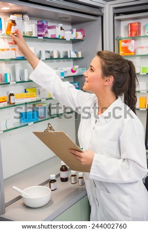 Junior pharmacist taking medicine from shelf at the hospital pharmacy