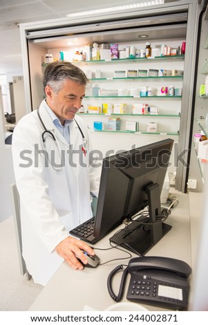 Senior pharmacist using the computer at the hospital pharmacy
