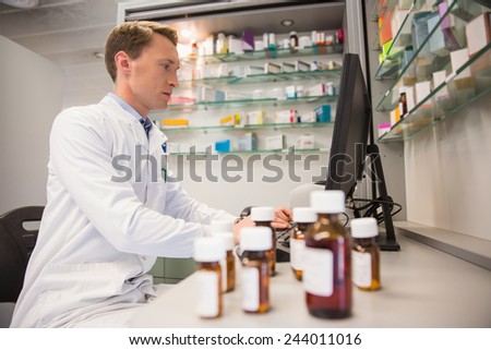 Pharmacist using computer at desk at the hospital pharmacy