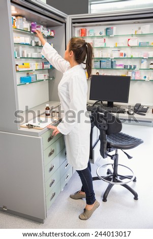 Junior pharmacist taking medicine from shelf at the hospital pharmacy