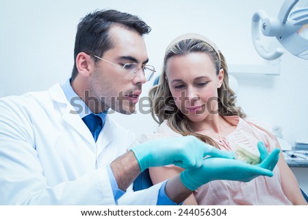 Male dentist showing woman prosthesis teeth in the dentists chair