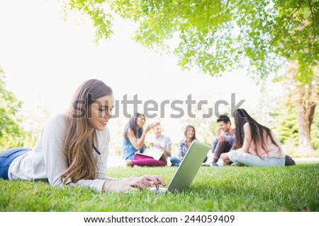 Happy student using her laptop outside at the university