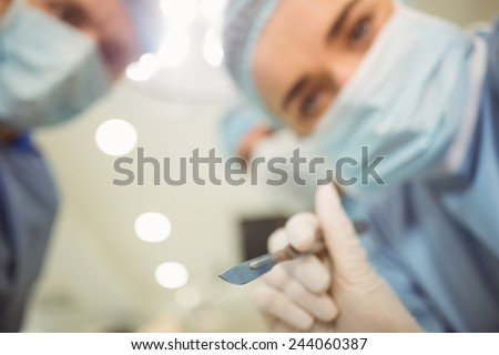 Young surgeons looking down at camera holding scalpel at the university
