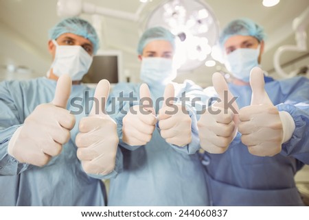 Team of surgeons looking at camera showing thumbs up at the university