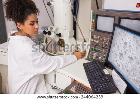 Biochemistry student using large microscope and computer at the university