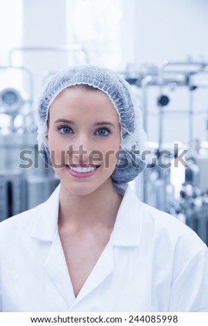 Portrait of a smiling scientist wearing hair net in the factory