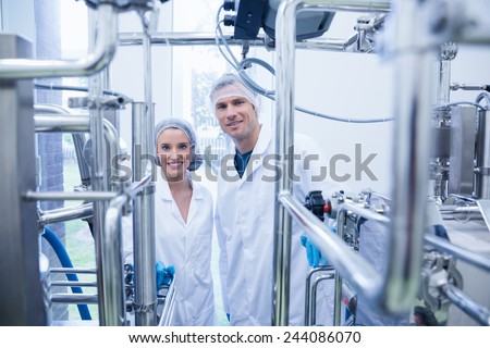 Scientist team behind metal gauge looking at camera in the factory