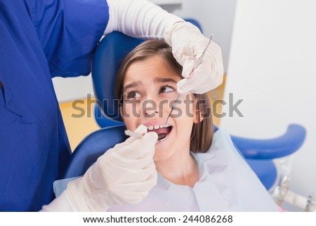 Pediatric dentist doing examination at a scared young patient in dental clinic
