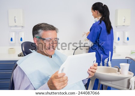 Smiling patient holding a mirror with a dentist behind him