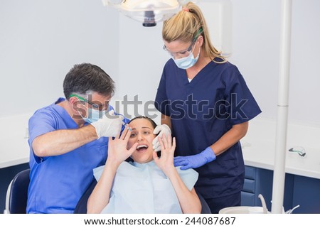 Dentist doing injection and patient protesting in dental clinic