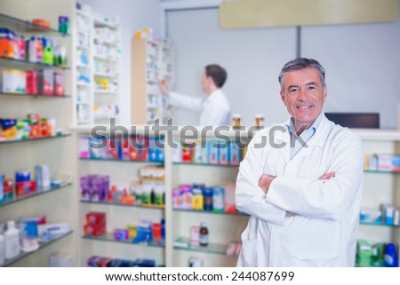 Smiling pharmacist standing with arms crossed in the pharmacy