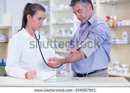 Trainee listening to patients pulse with stethoscope in the pharmacy