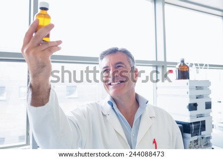Smiling scientist in lab coat holding a chemical bottle in laboratory
