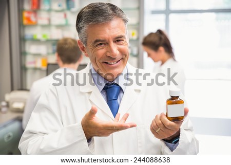Senior pharmacist showing medicine jar at the hospital pharmacy