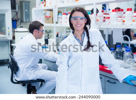Portrait of a smiling chemist leaning against desk in the laboratory