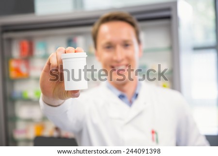 Handsome pharmacist showing medicine jar at the hospital pharmacy