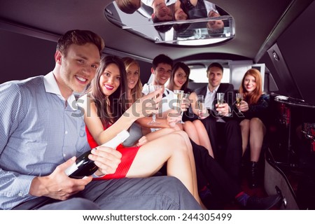 Happy friends drinking champagne in limousine on a night out