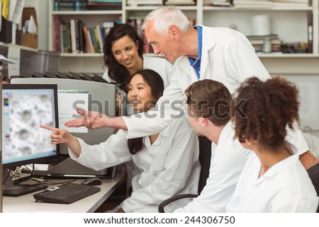 Science students looking at microscopic image on computer with lecturer at the university