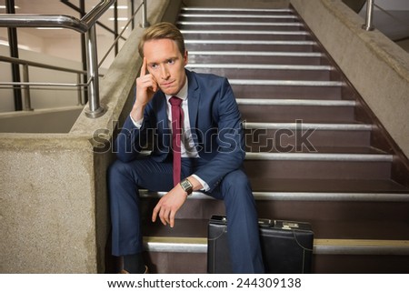 Stressed businessman sitting on steps in office building