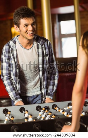 A brown hair playing table football with friends in a bar