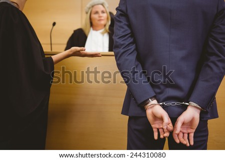 Judge talking with the criminal in handcuffs in the court room
