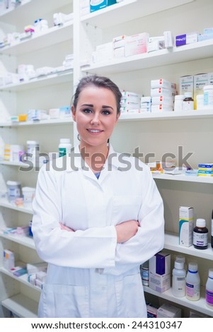 Portrait of a smiling student in lab coat with arms crossed in the pharmacy