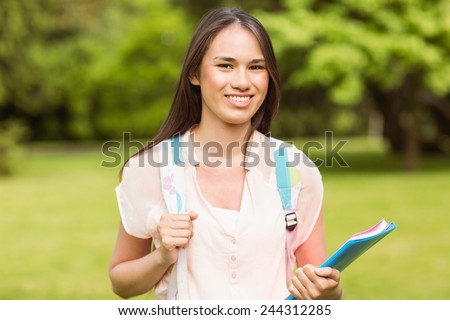 Portrait of a smiling student with a shoulder bag in park at school
