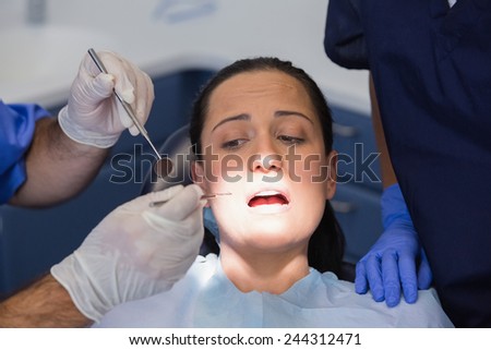 Dentist and nurse examining a scared patient in dental clinic