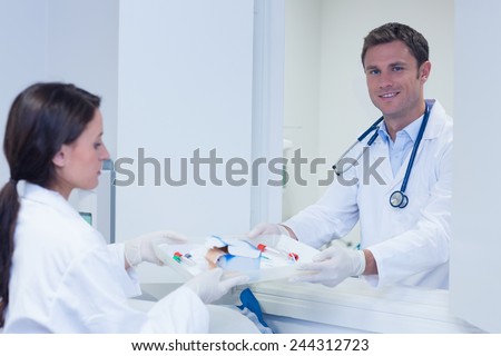 Doctor giving tray with blood sample to his colleague in hospital