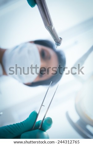 Low angle view of female dentist in surgical mask holding dental tools