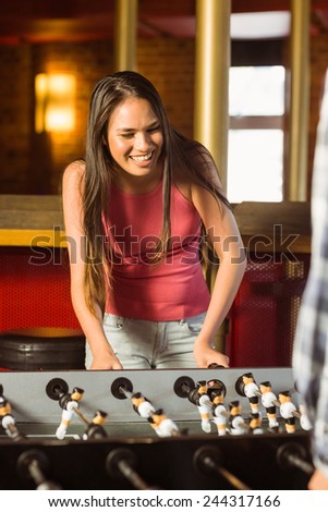 A brunette playing table football with friends in a bar
